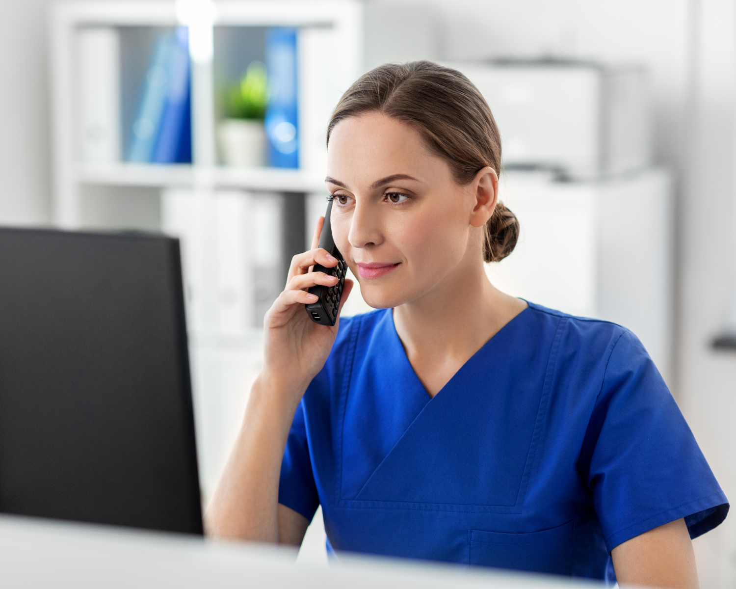 A person in blue scrubs talking on a phone