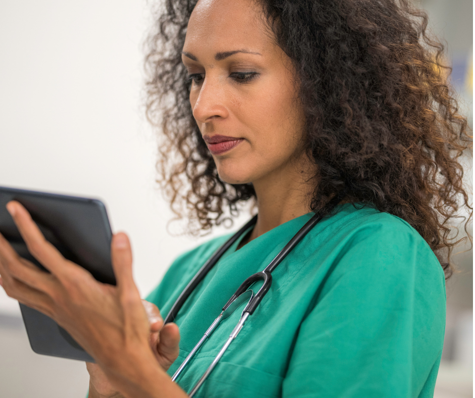 Veterinary staff member in scrubs reviewing patient charts and tasks on a tablet